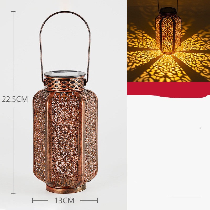 Lanterne solaire Lumeoo en métal ajouré couleur bronze avec motifs décoratifs projetant une lumière chaleureuse