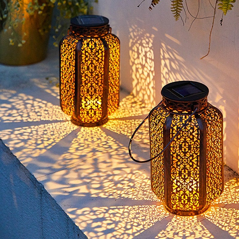 Lanterne solaire décorative Lumeoo avec motifs ajourés projetant des ombres lumineuses sur une terrasse extérieure