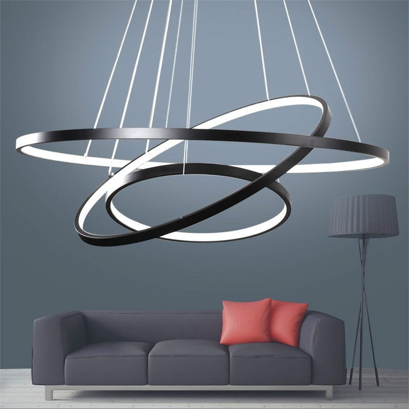 Lustre LED Lumeoo CIRCOLUX à anneaux circulaires noirs suspendus au-dessus d'un canapé gris dans un salon moderne.