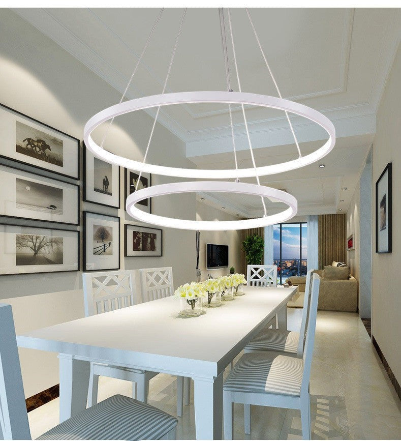 Lustre LED Lumeoo à deux anneaux blancs suspendus au-dessus d'une table de salle à manger moderne et lumineuse