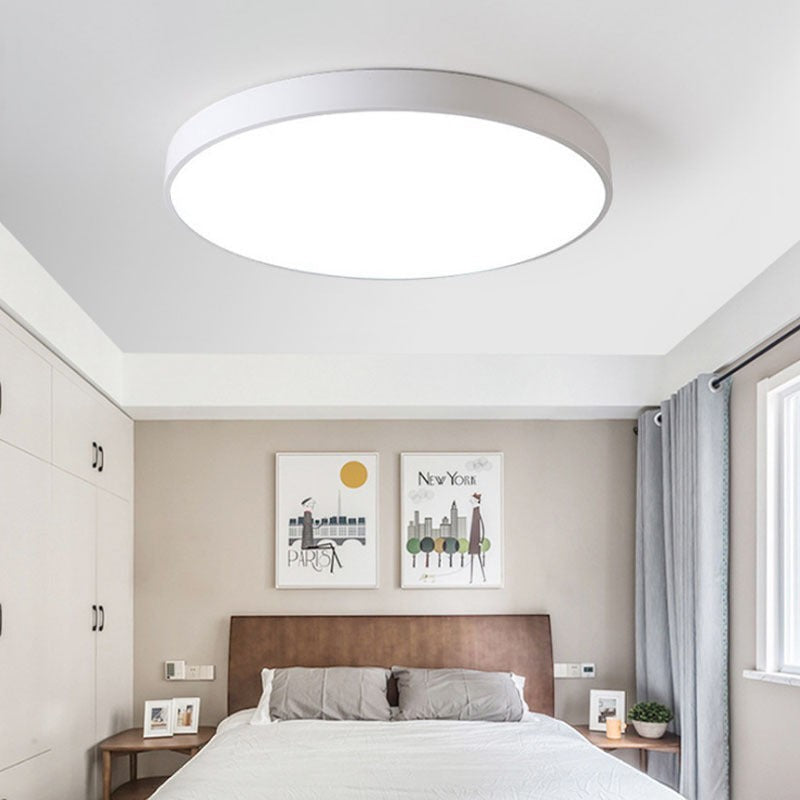 Plafonnier LED rond ultra-fin Lumeoo blanc minimaliste installé au plafond d'une chambre moderne et lumineuse