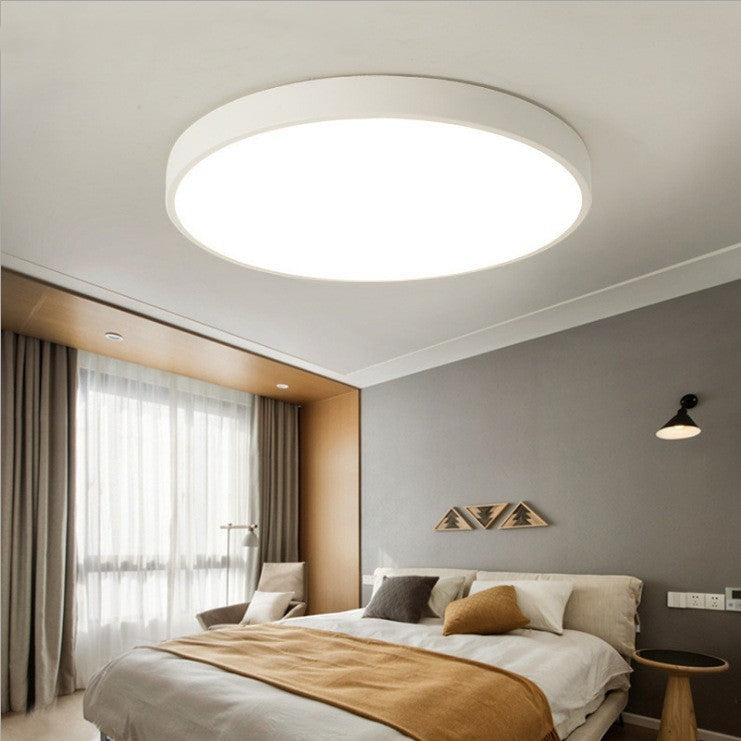Plafonnier LED rond ultra-fin Lumeoo blanc minimaliste installé au plafond d'une chambre moderne et chaleureuse