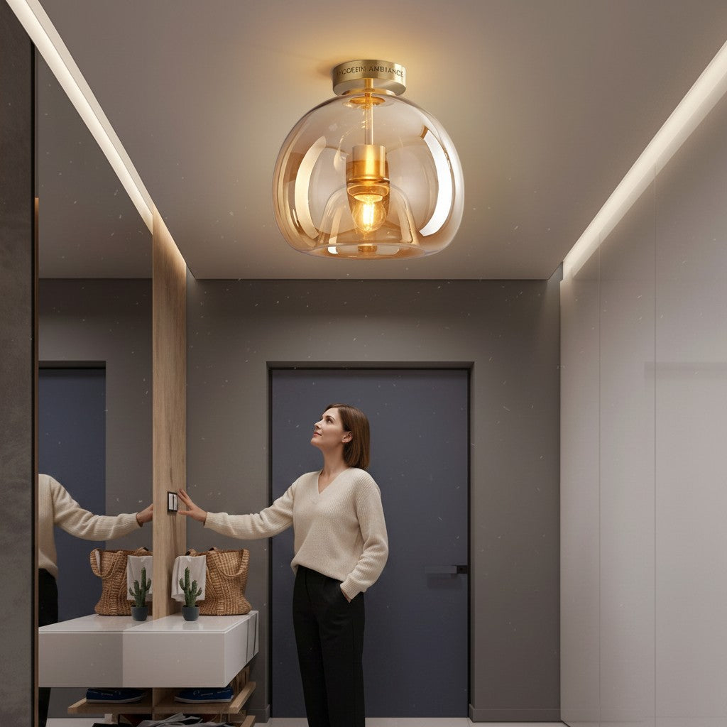 Plafonnier LED Lumeoo en verre ambré et métal doré dans une entrée moderne avec une femme allumant la lumière