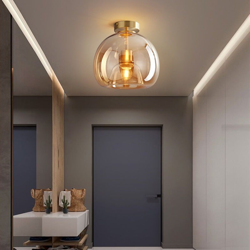 Plafonnier LED Lumeoo en verre ambré et métal doré au design moderne et luxueux installé dans une entrée élégante