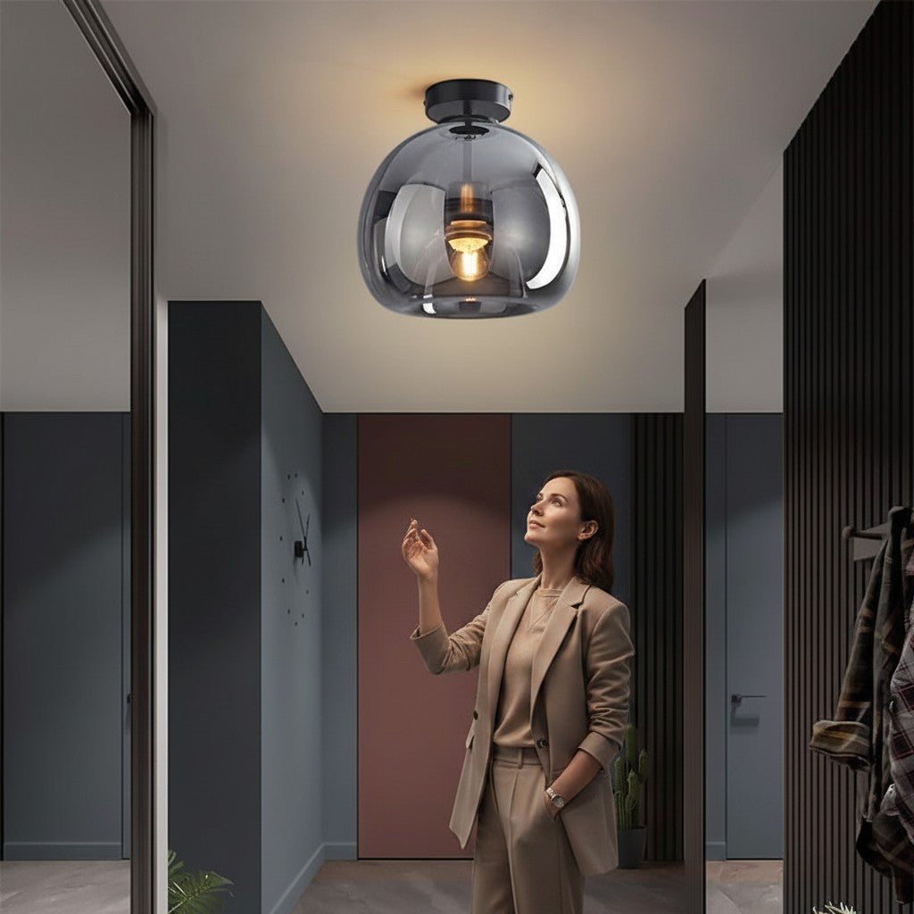 Plafonnier LED Lumeoo en verre fumé design moderne installé dans un intérieur élégant avec une femme admirant la lumière