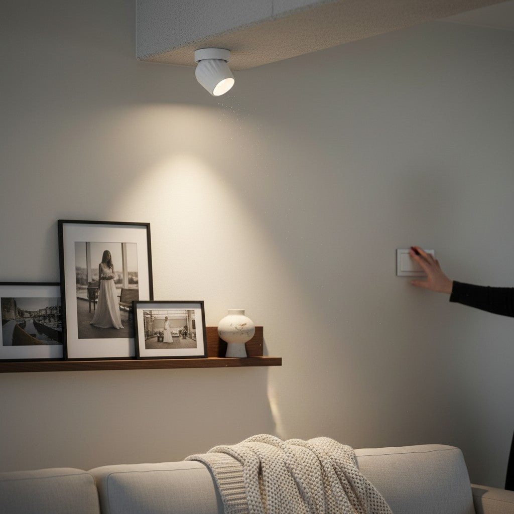 Plafonnier spot LED orientable blanc Lumeoo éclairant un mur avec des cadres photo dans un salon moderne