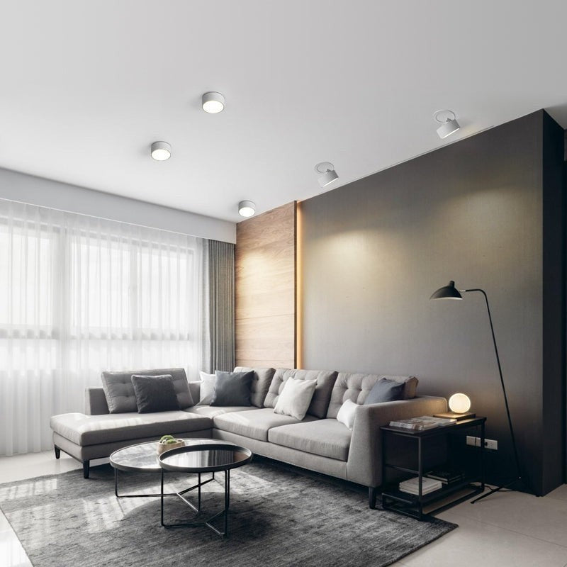 Spots LED encastrables orientables Lumeoo blancs installés au plafond d'un salon moderne avec canapé gris