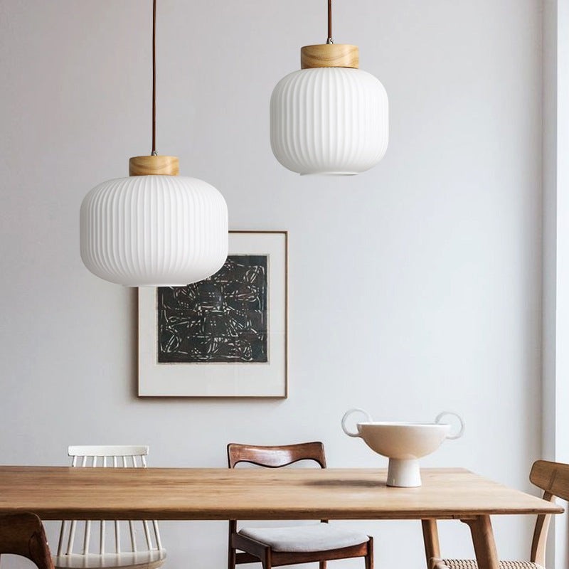 Suspension Lumeoo en bois et verre blanc strié au-dessus d'une table en bois dans une salle à manger lumineuse Image