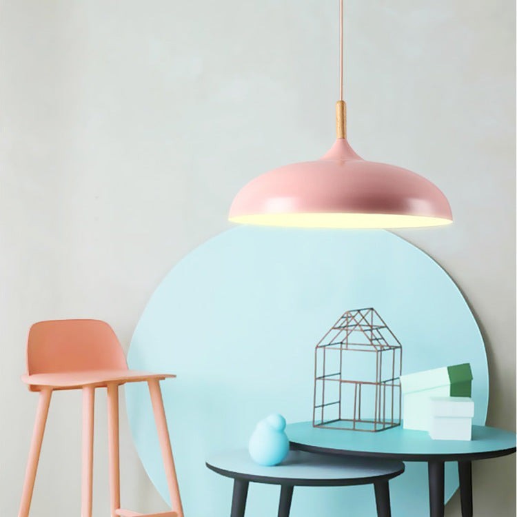 Suspension Lumeoo rose pastel au design scandinave minimaliste avec détail en bois clair au-dessus d'une table