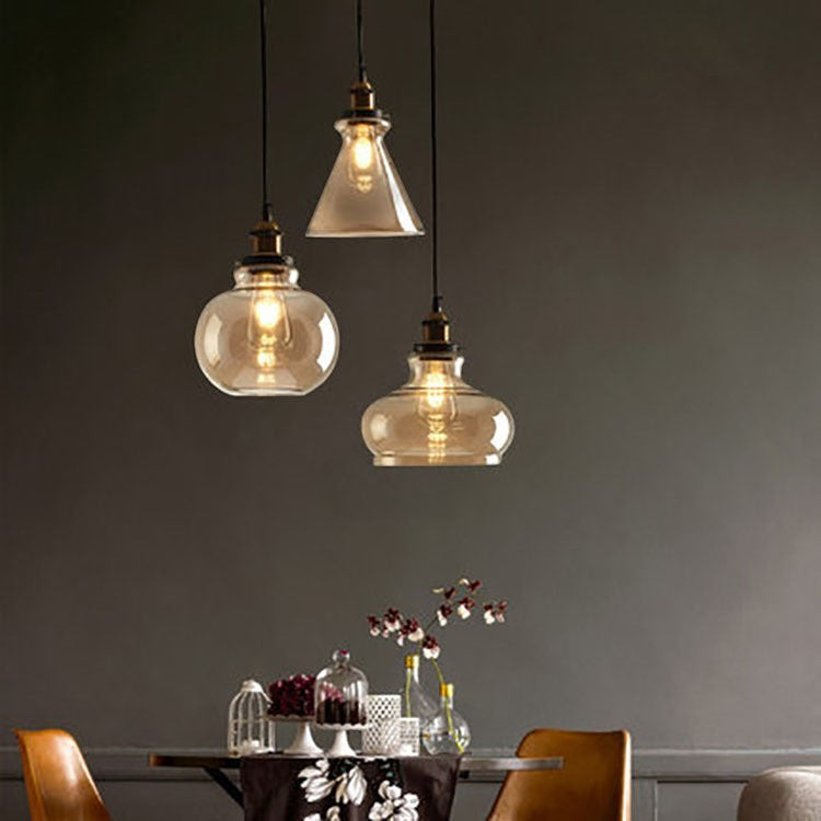 Suspension Lumeoo en verre fumé vintage avec trois lampes aux formes variées diffusant une lumière douce et chaleureuse
